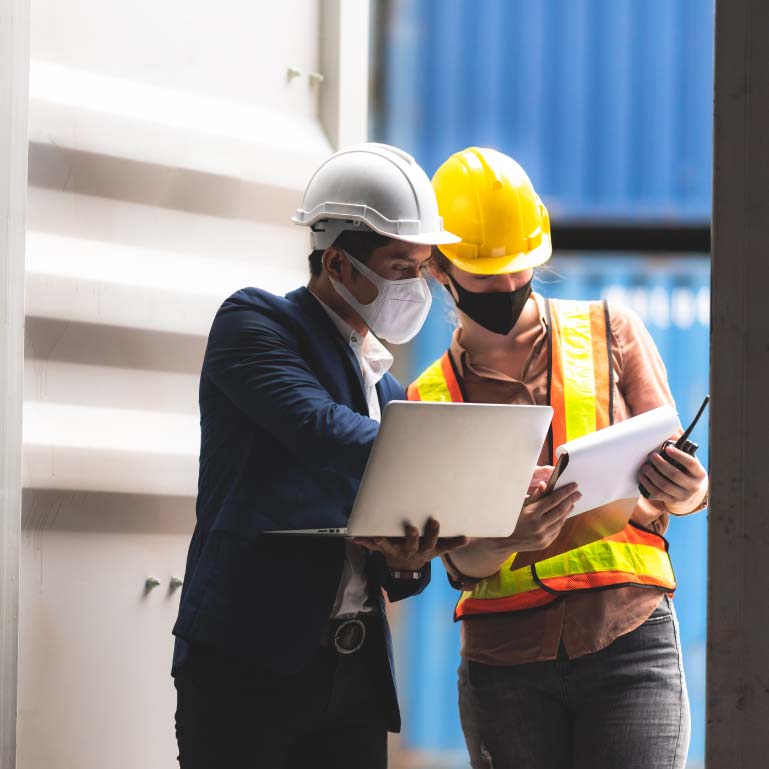 Two employees wearing masks and safety gear in loading dock